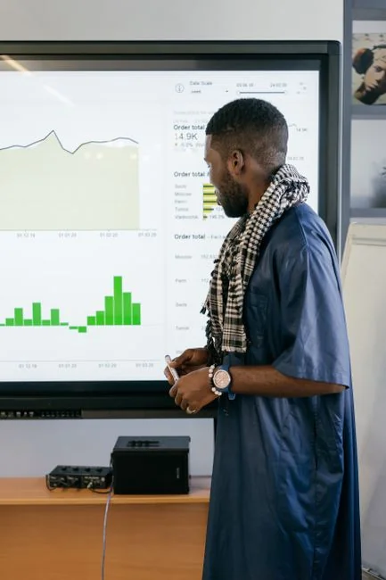 Person analyzes stock data with a smartphone and laptop, indoors.